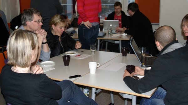 Pedagoger sitter och diskuterar runt bord.