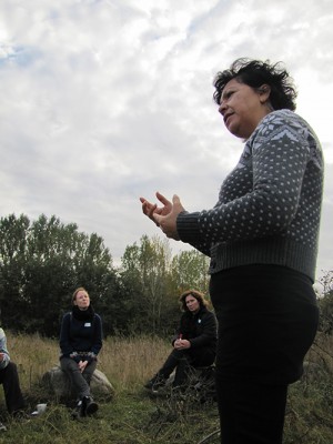 Elizabeth Florez föreläser för pedagoger som sitter på stenar på äng.