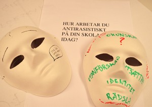 Två masker ligger på papper med fråga om hur du arbetar antirasistiskt på din skola.