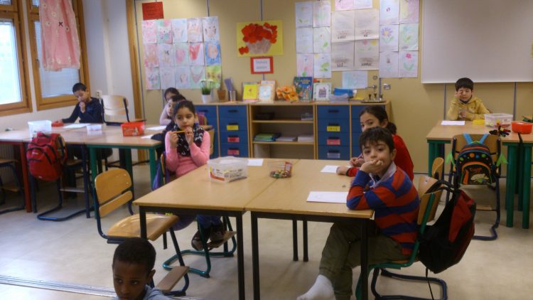 Barn i bänkar lyssnar på pedagog.