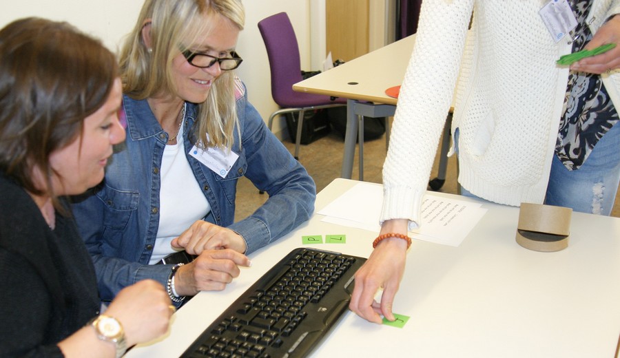 Grön lapp delas ut till två kvinnor som sitter vid tangentbord.