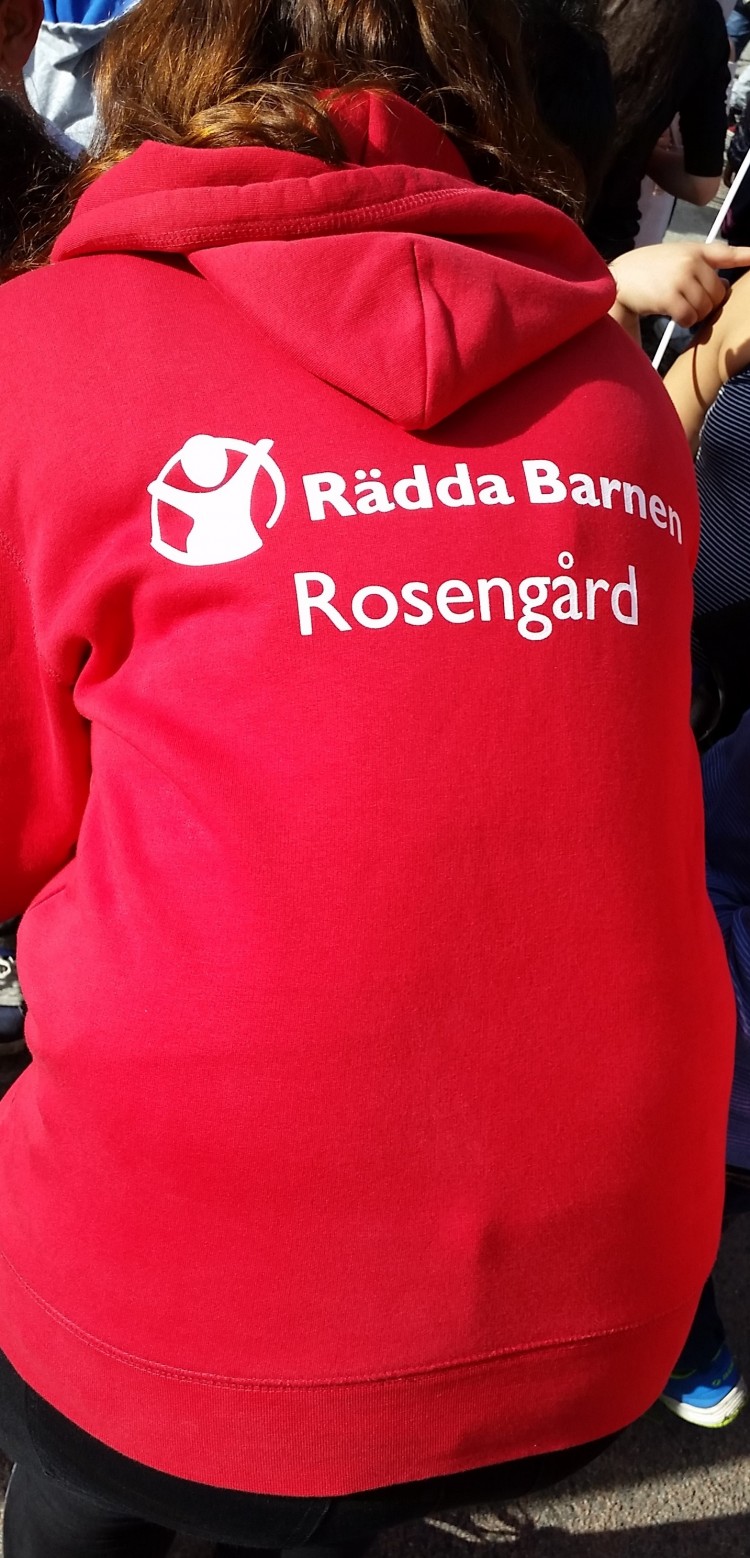 Kvinna med röd tröja där det står Rädda barnen Rosengård.