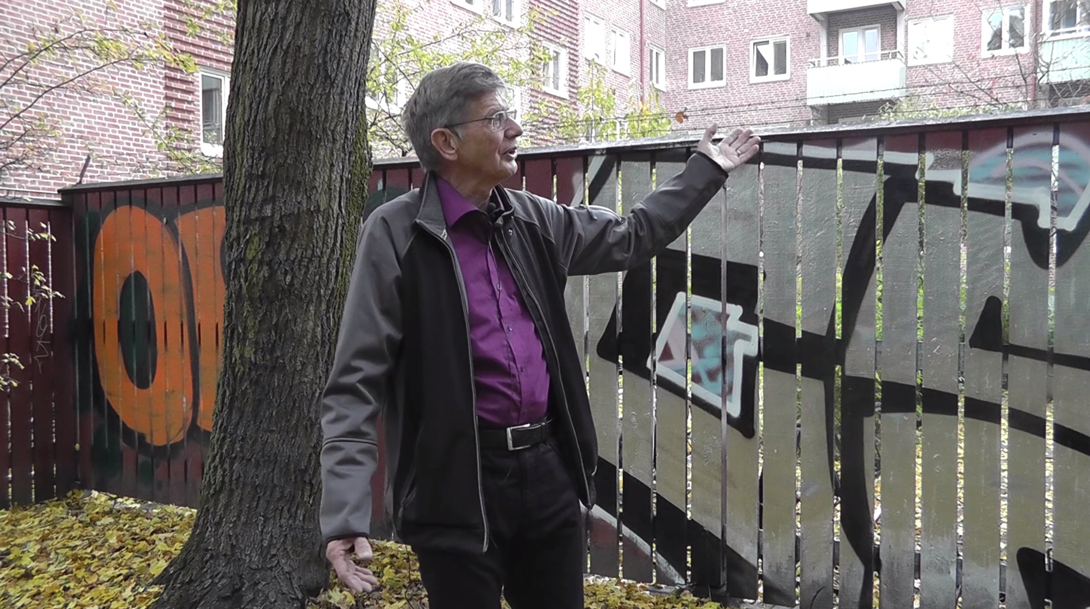 Bertil framför plank med grafitti.