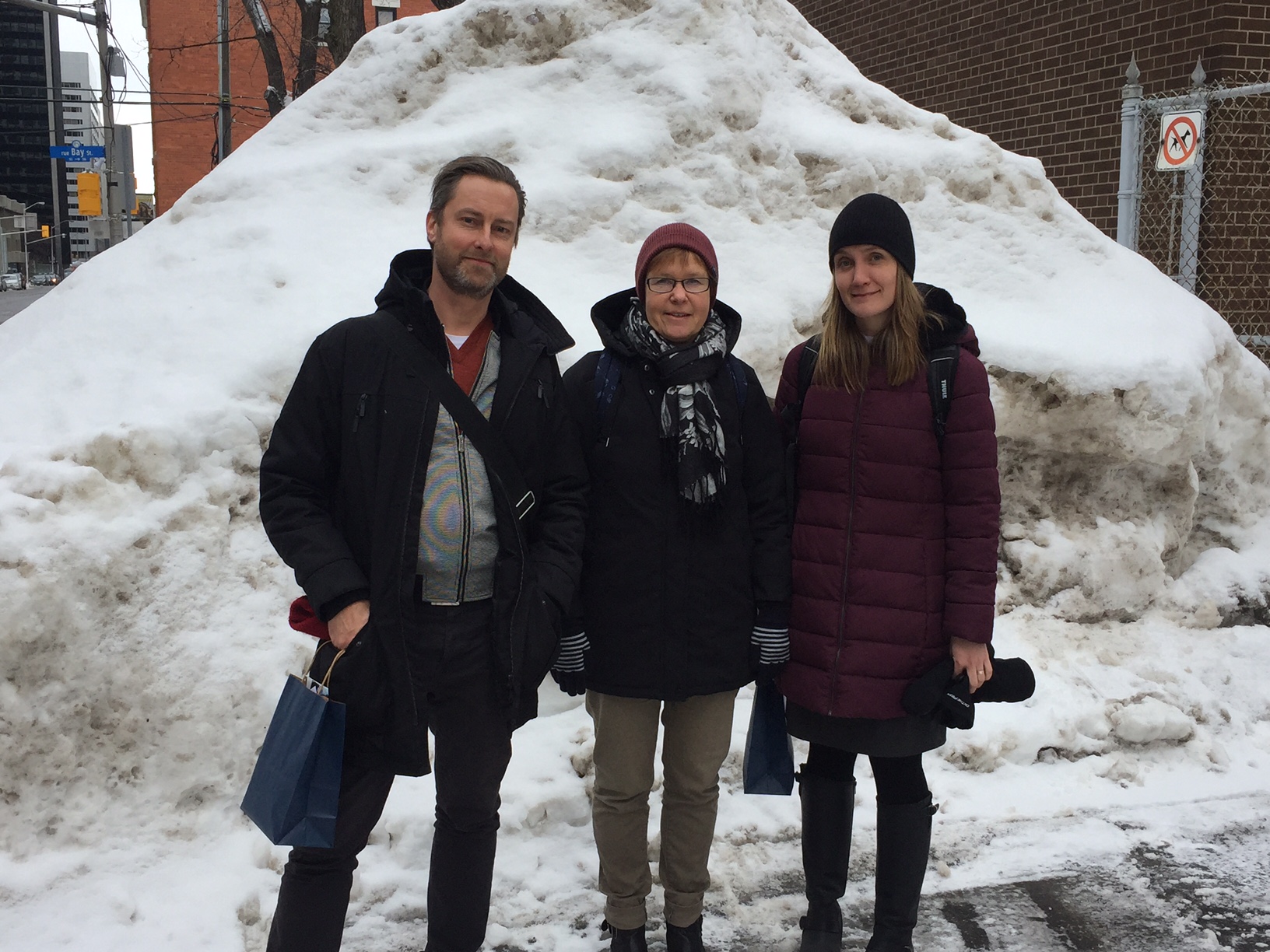 Tre personer framför snöhög.