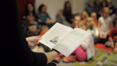 Pedagog håller i uppslagen bok.