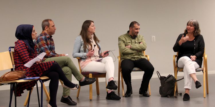 Fem personer sitter på scen i panelsamtal.