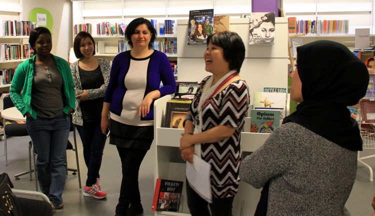 Fem kvinnor står i bibliotek.