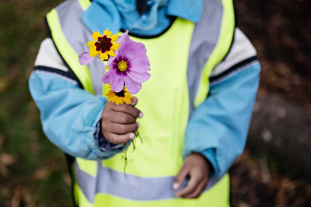 Barn håller upp bukett med blommor.