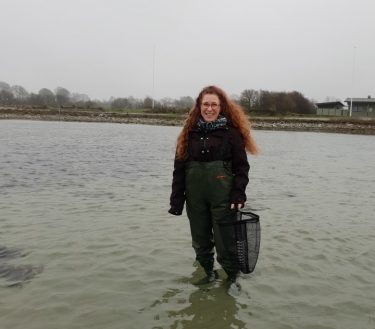 Katrina Fornell står i havet med vadarbyxor på.