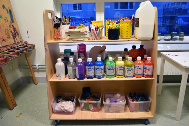 Målarburkar, pennor, saxar och andra verktyg står på en vagn i ateljén på Ribersborgs förskola.
