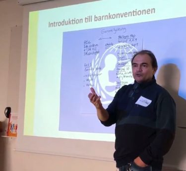 En man står framför en projicerad bild om barnkonventionen.