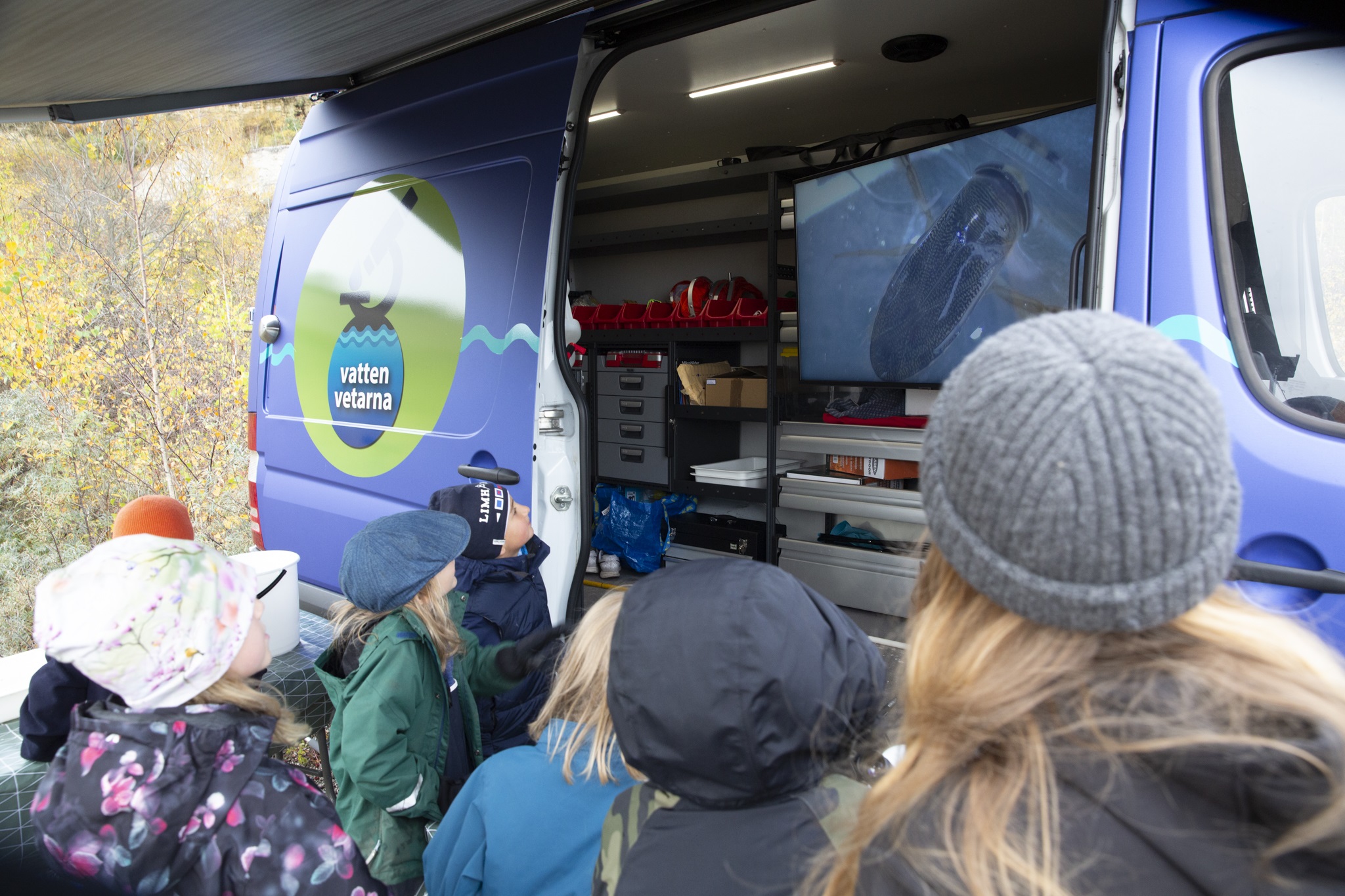 Bilden visar barn som står framför vattenvetarbussen.