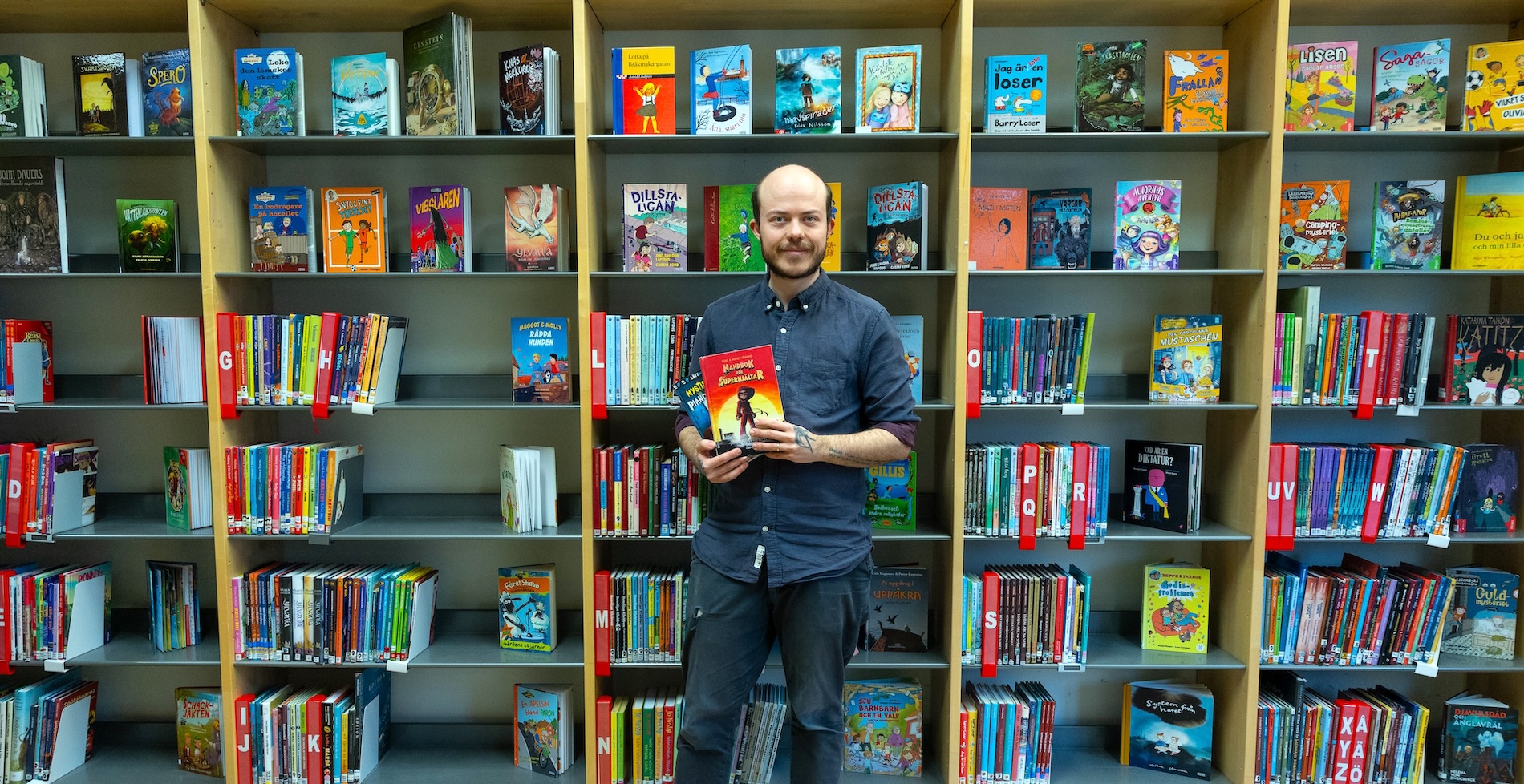 Felix Sjögren står framför bokhyllor i Nydalaskolans bibliotek.