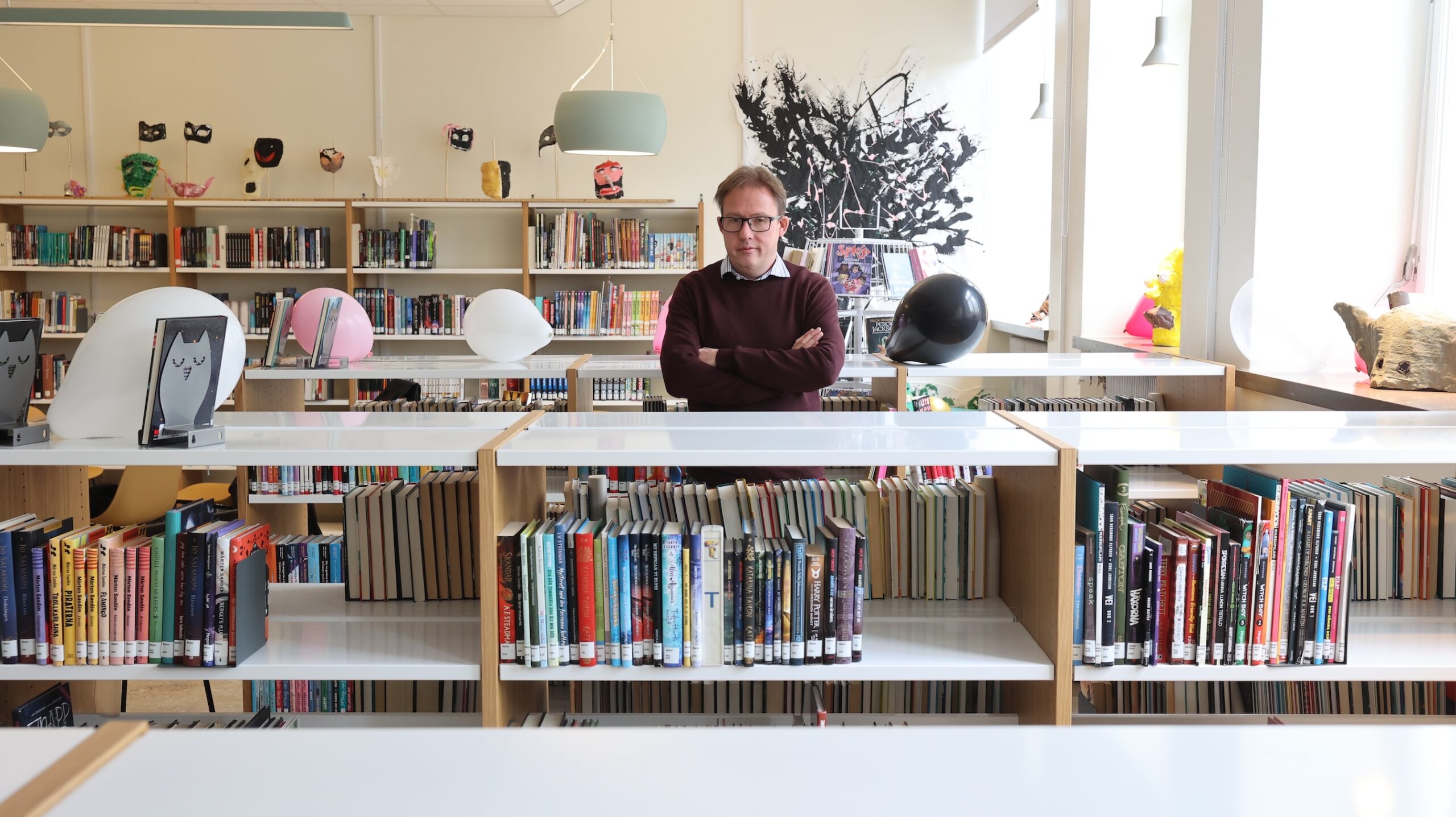 En bibliotekarie står bland bokhyllorna på ett bibliotek.