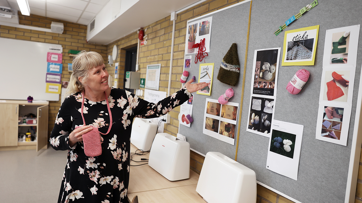 Helene Richter visar upp anslagstavla med bildstöd: garnnystan i olika färger.