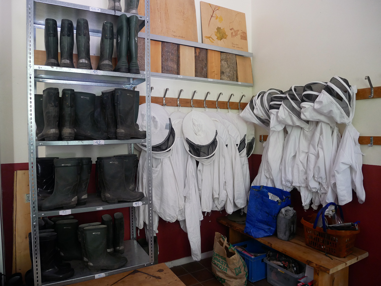 Arbetskläder för biodling i en hall; stövlar och skyddande biodlardräkter.