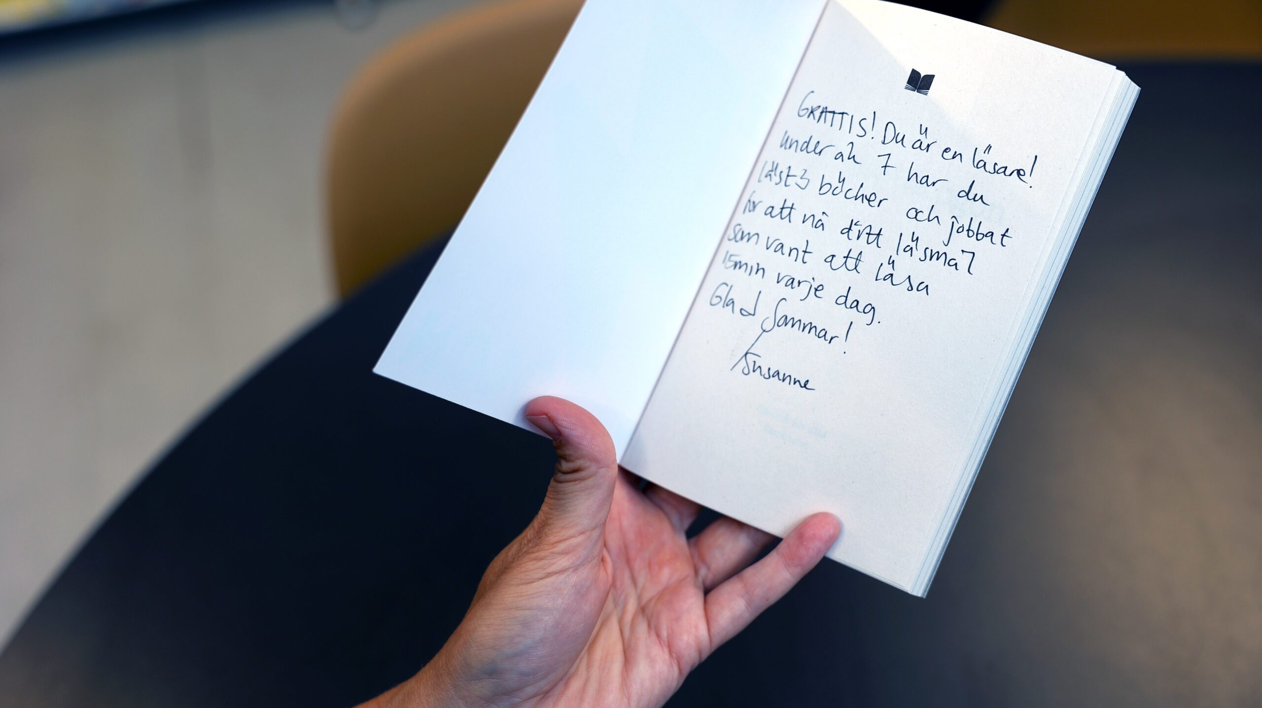 En hälsning från bibliotekarien till en elev står skriven i en bok.