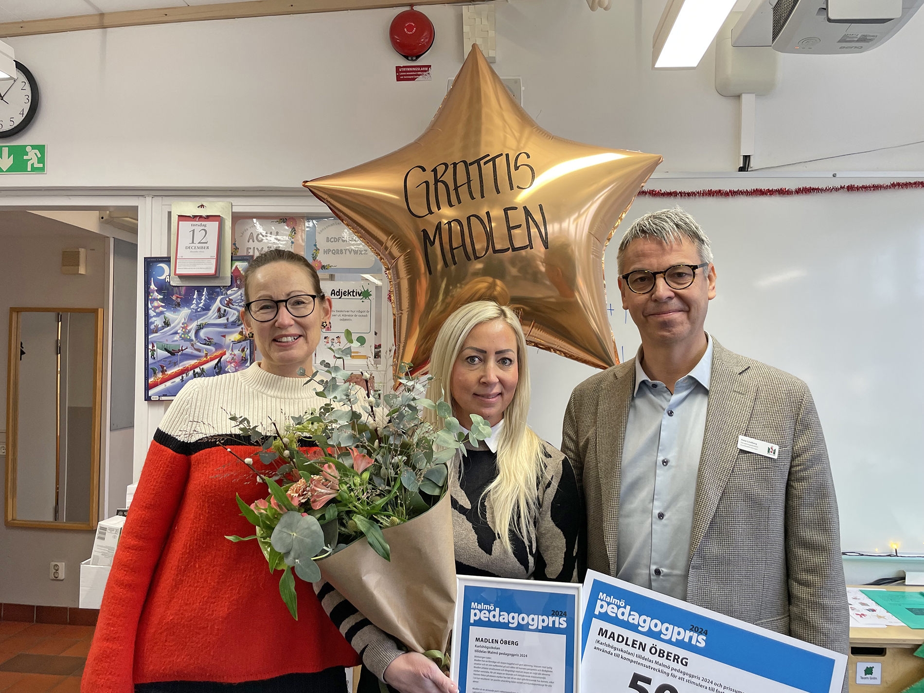 Sara Wettergren, Madlen Öberg och Peter Lindberg med blommor, prischeck och ballong med texten 'Grattis Madlen'.
