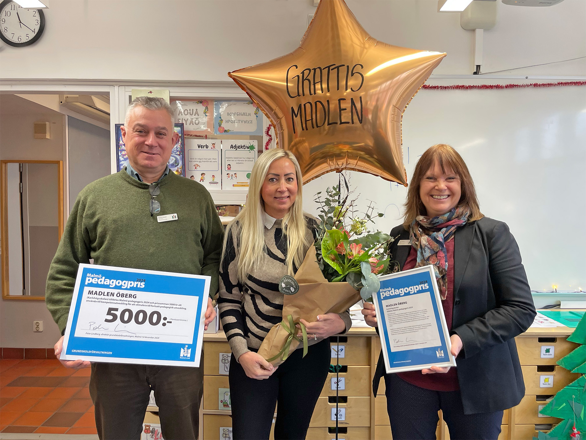 Rickard Sjövall, Madlen Öberg och Marie Wesén med prischeck, blommor och ballong med texten 'Grattis Madlen'.