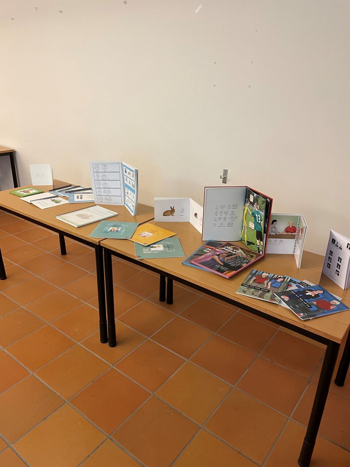 En rad böcker ligger och står uppställda på ett par bord.