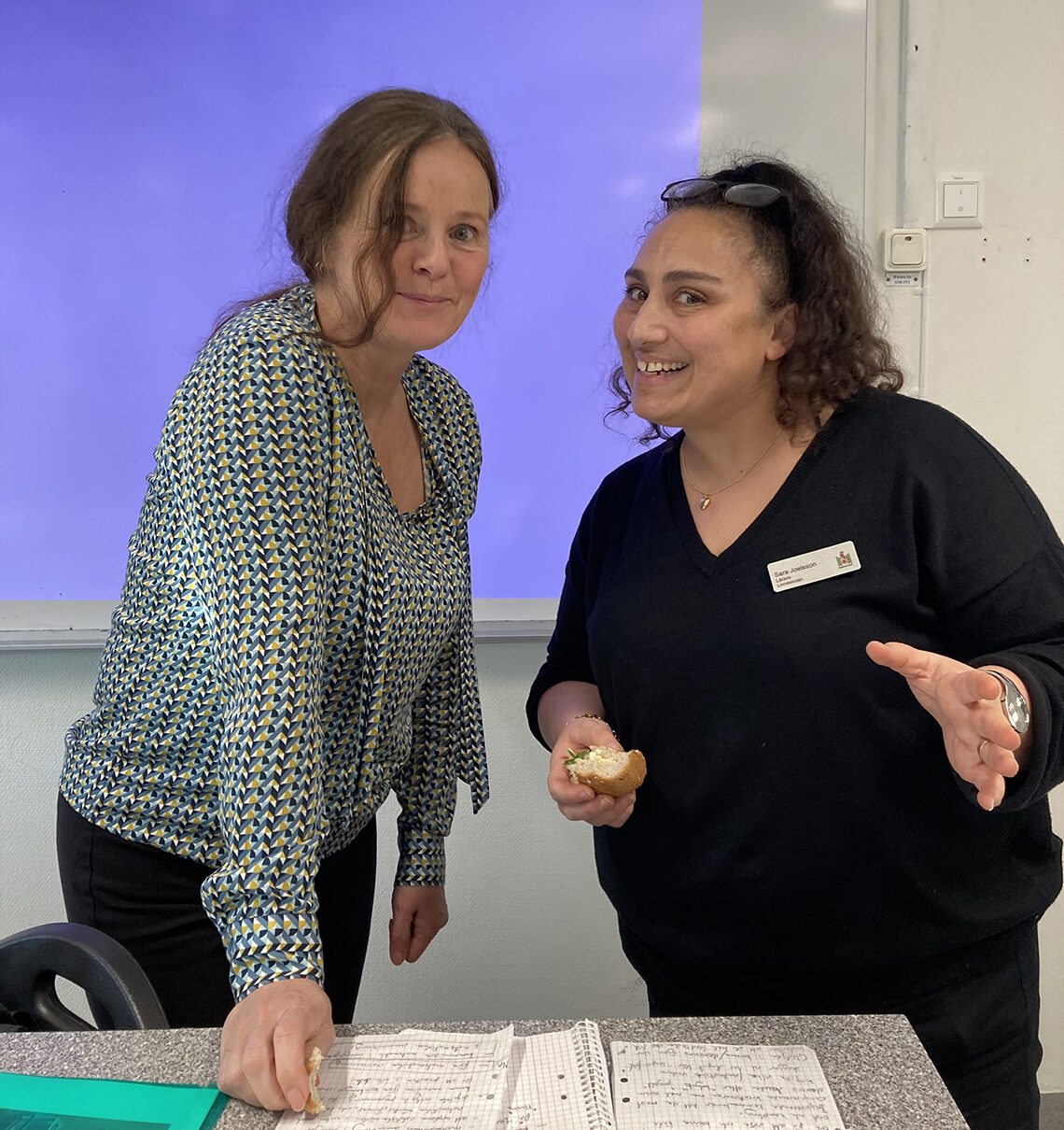 Karin och Sara står bakom katedern och tittar glatt mot kameran.