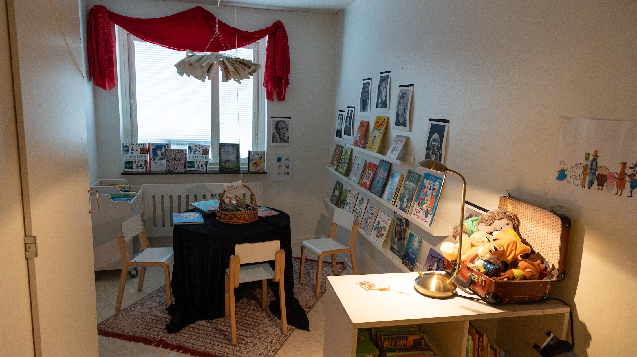 Ett rum för läsning, med böcker på hyllor och författarporträtt på väggarna.