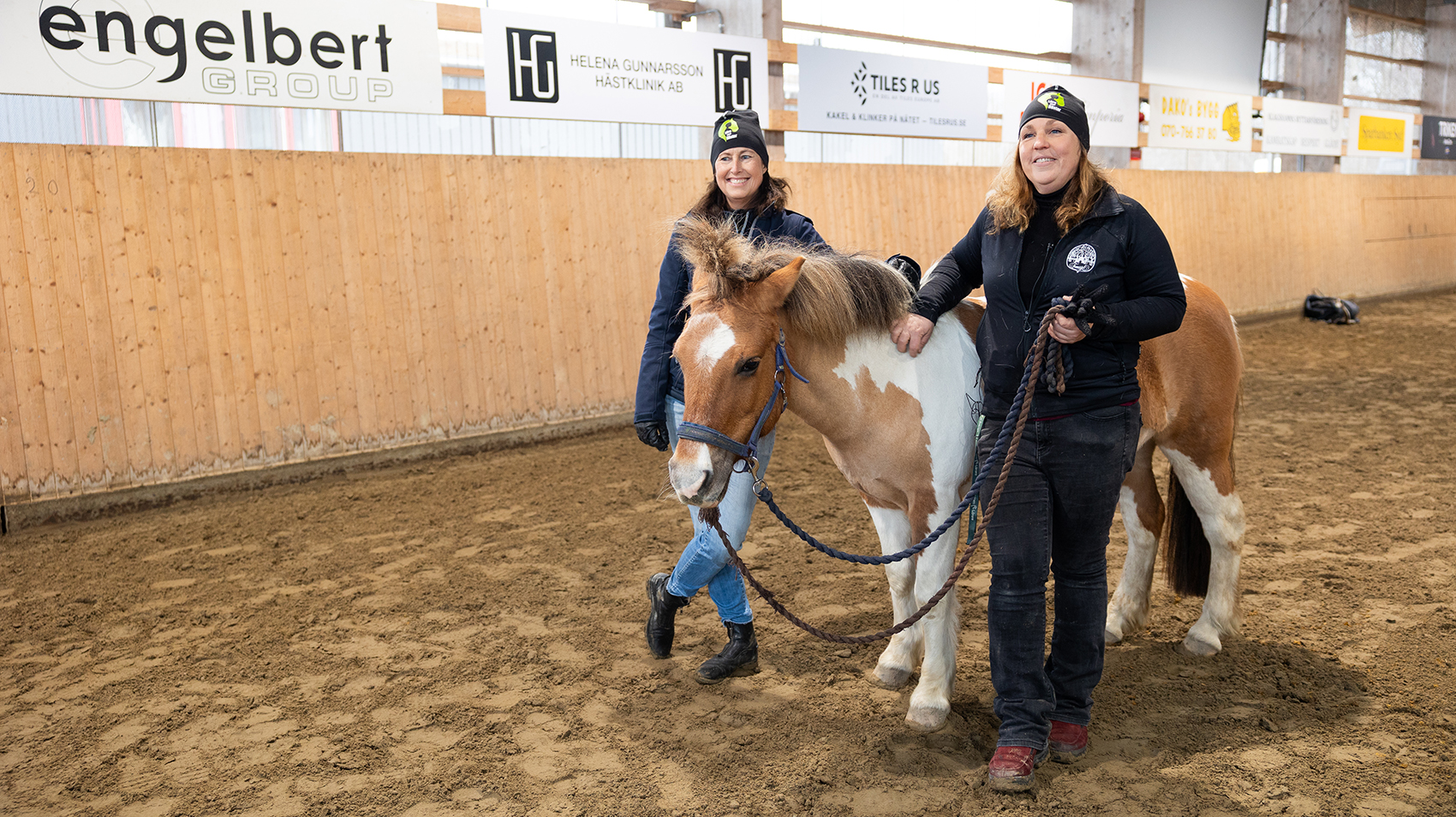 Två kvinnor och en ponny i ridhus.