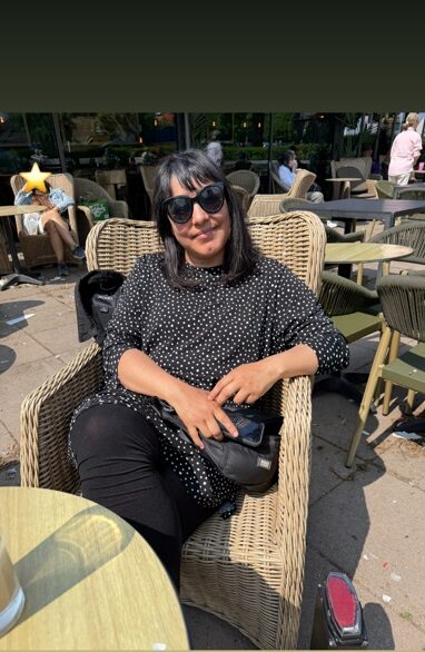 Catalina sitter i en korgstol på en uteservering.