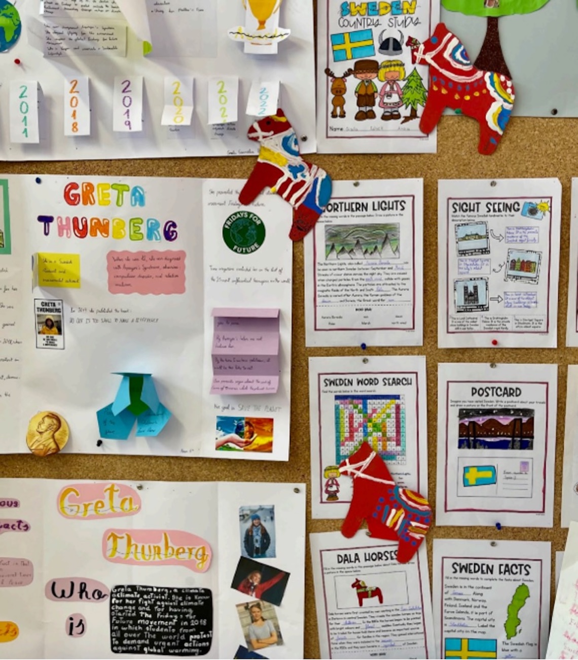 Elevarbeten om Sverige sitter uppsatta på en tavla. Här nämns norrsken och Greta Thunberg.