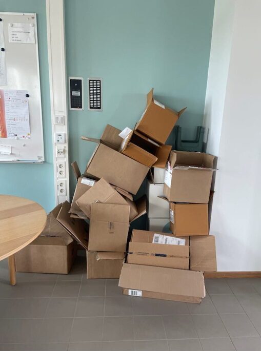 En hög med kartonger ligger huller om buller i ett hörn.