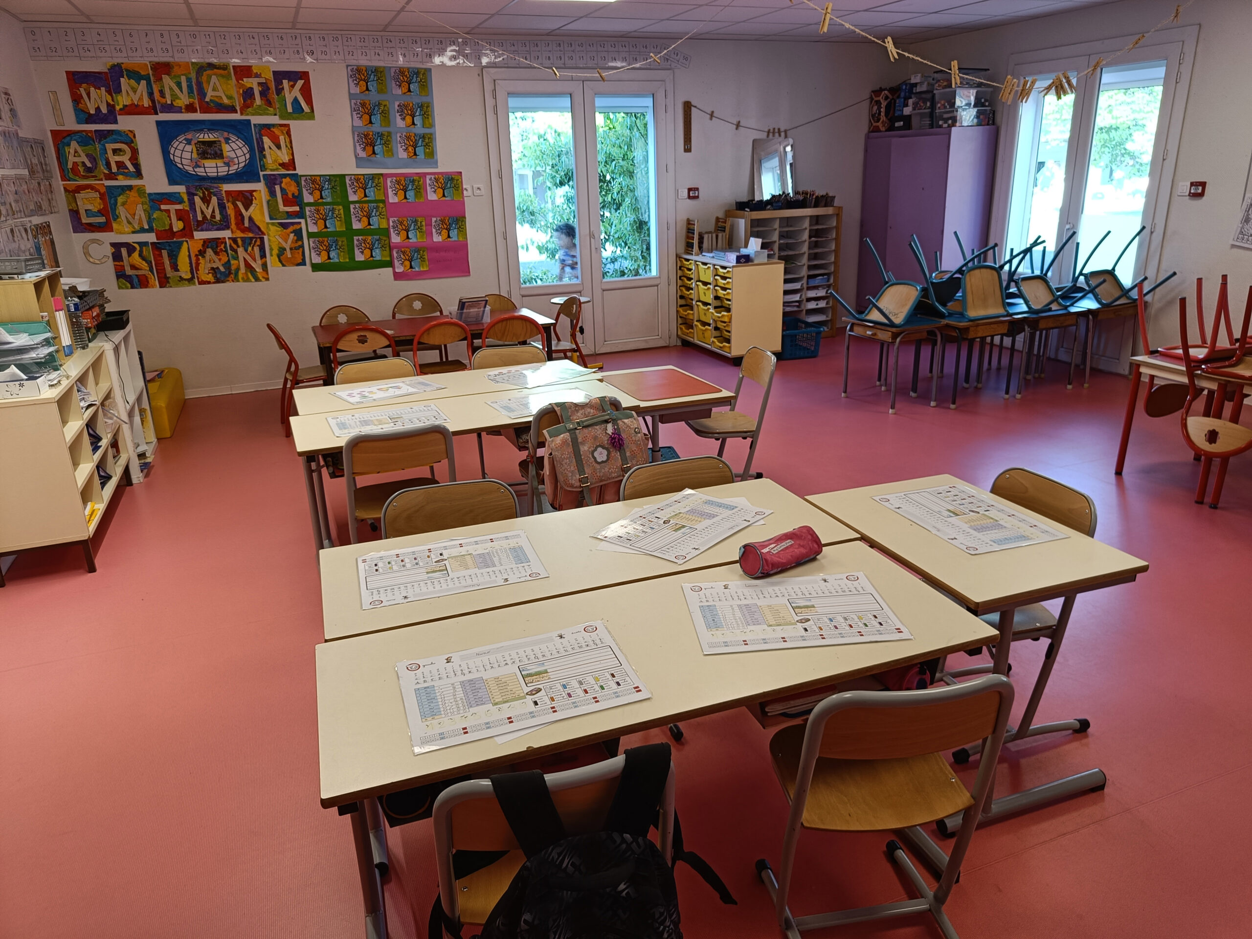 Interiör från ett klassrum. Fem stolar står vid varje bord och på några stolar hänger ryggsäckar.