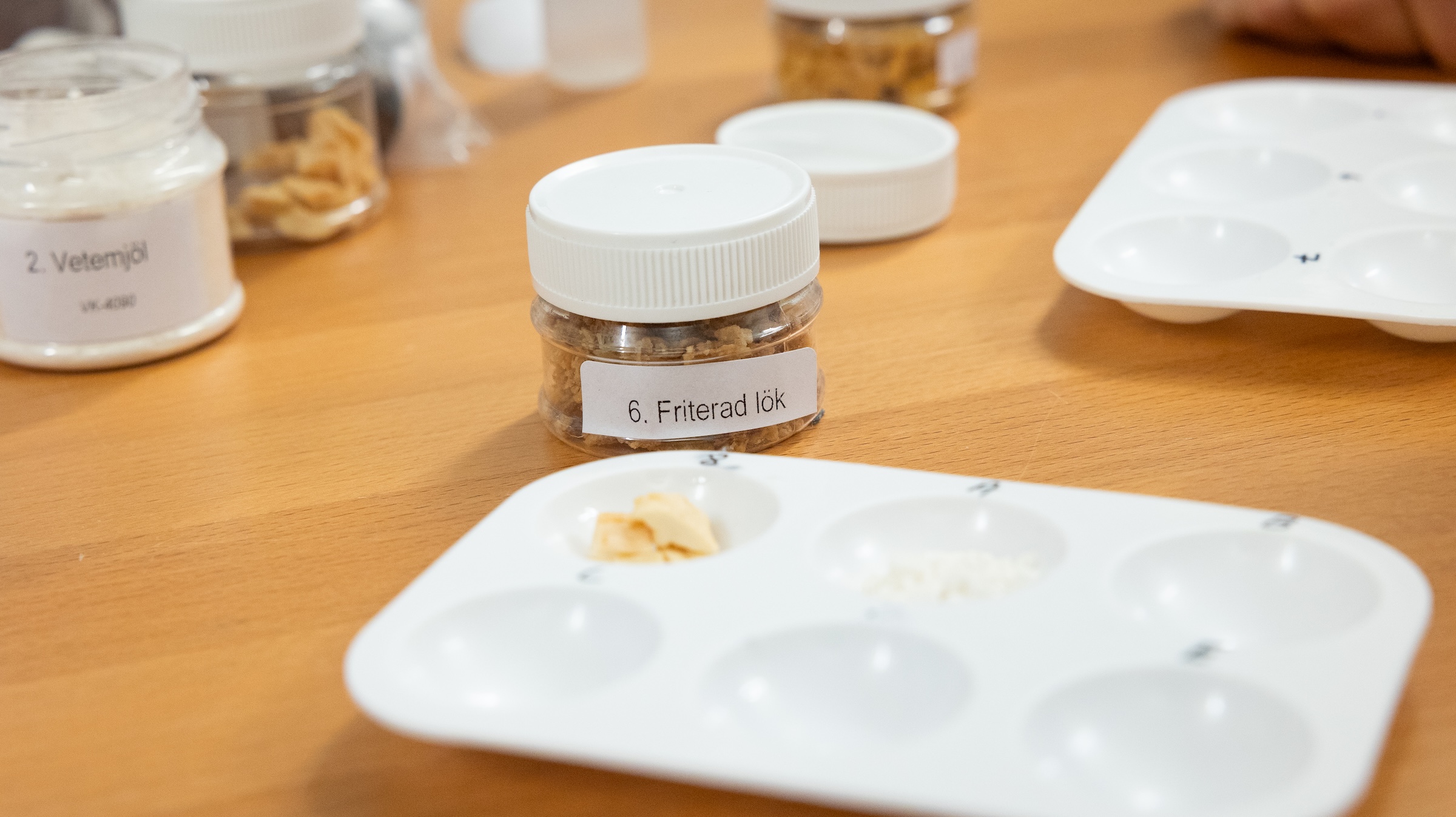 Närbild på glasburkar med etiketterna 'Friterad lök' och 'Vetemjöl'.