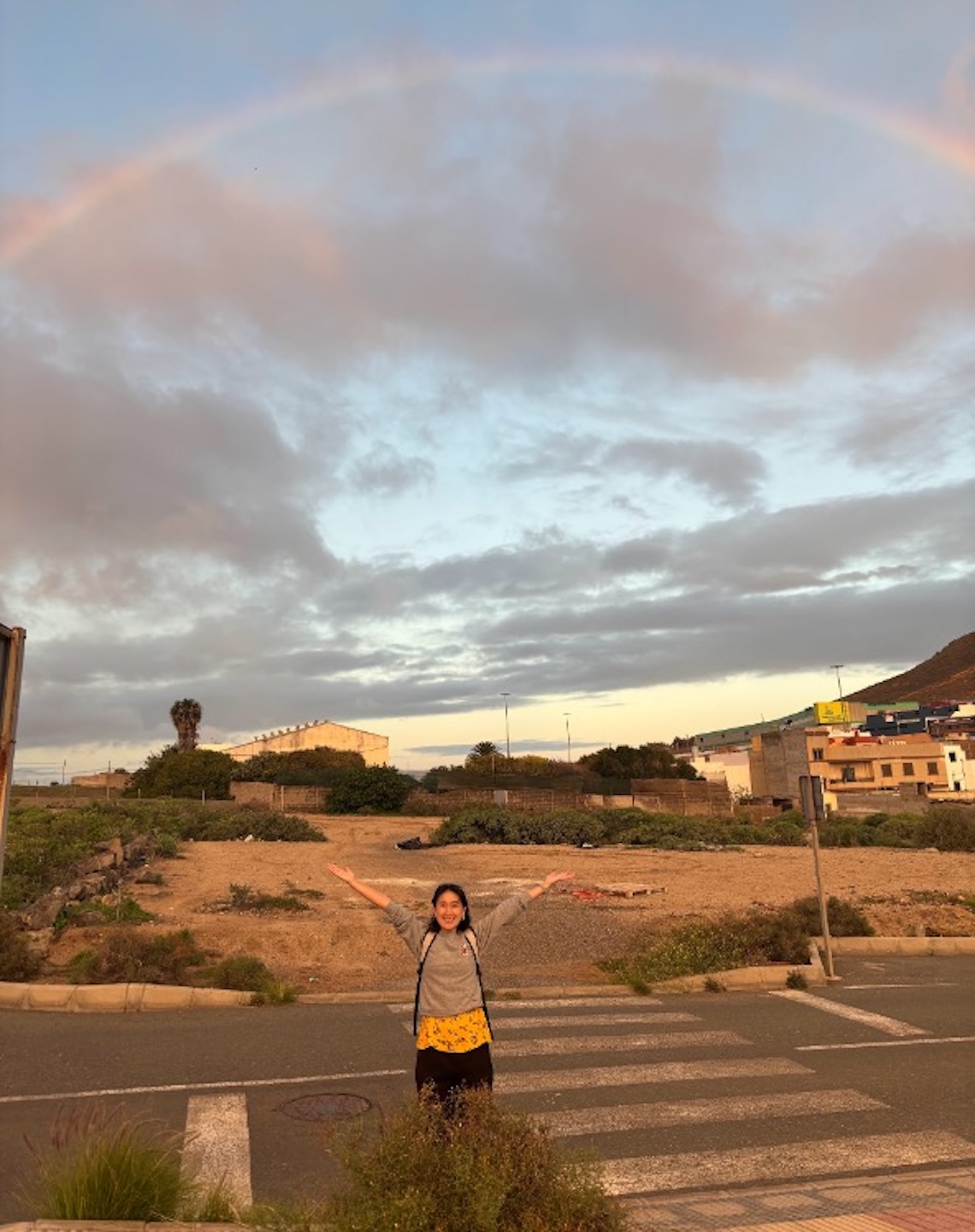 En elev på resa ser glad ut och sträcker händerna mot kvällshimlen på Gran Canaria.