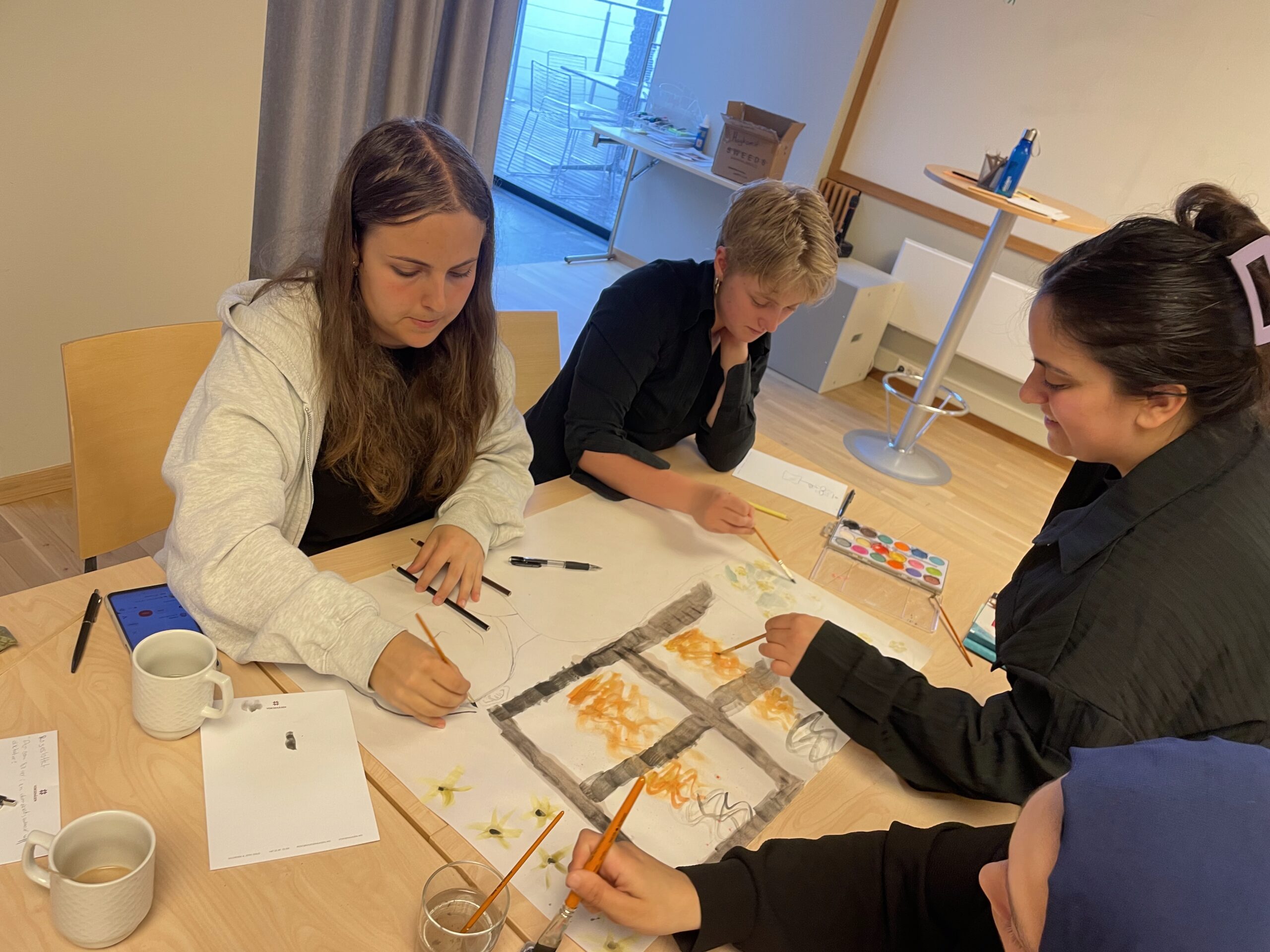 Fyra elever målar på papper.