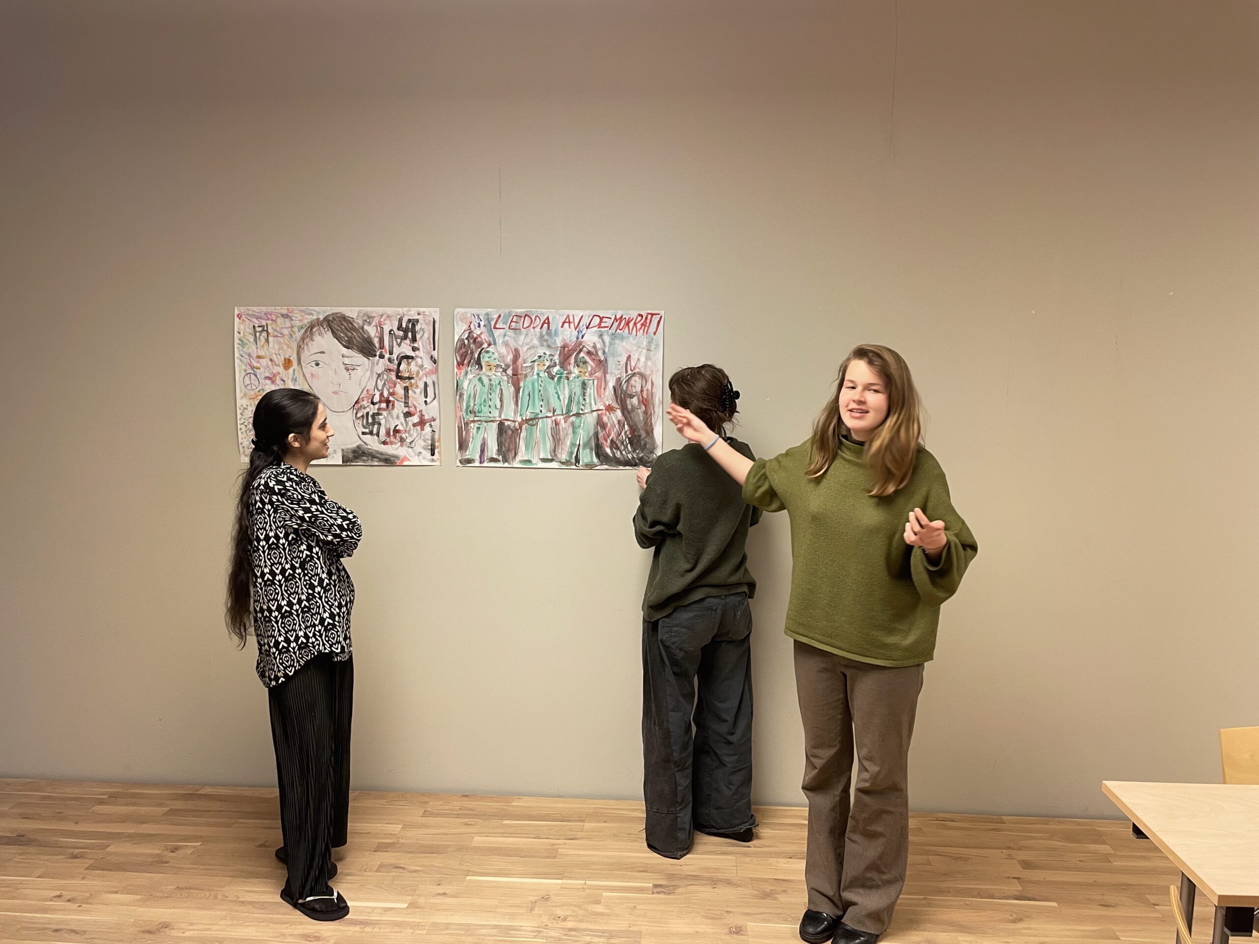 Elever har en presentation framför ett par uppsatta målade bilder på väggen.