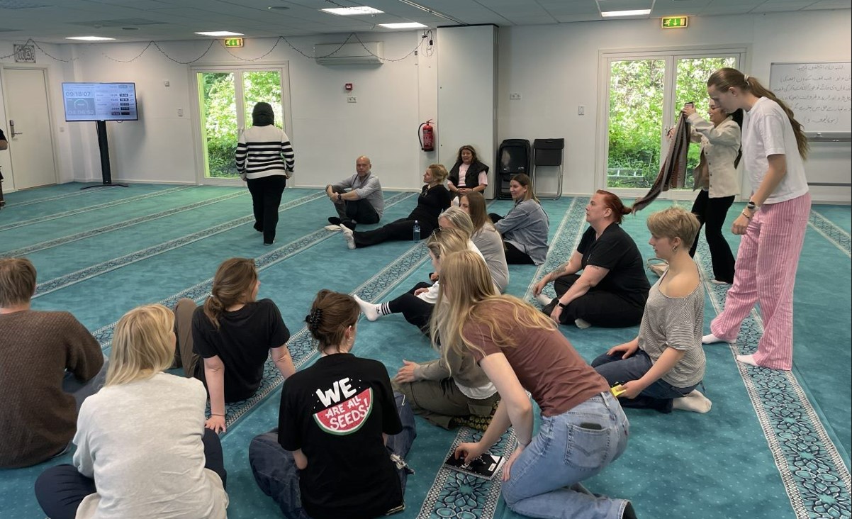 Elever sitter på golv prydd med en matta i Al-Noor moskén, två mil väster om Oslo.