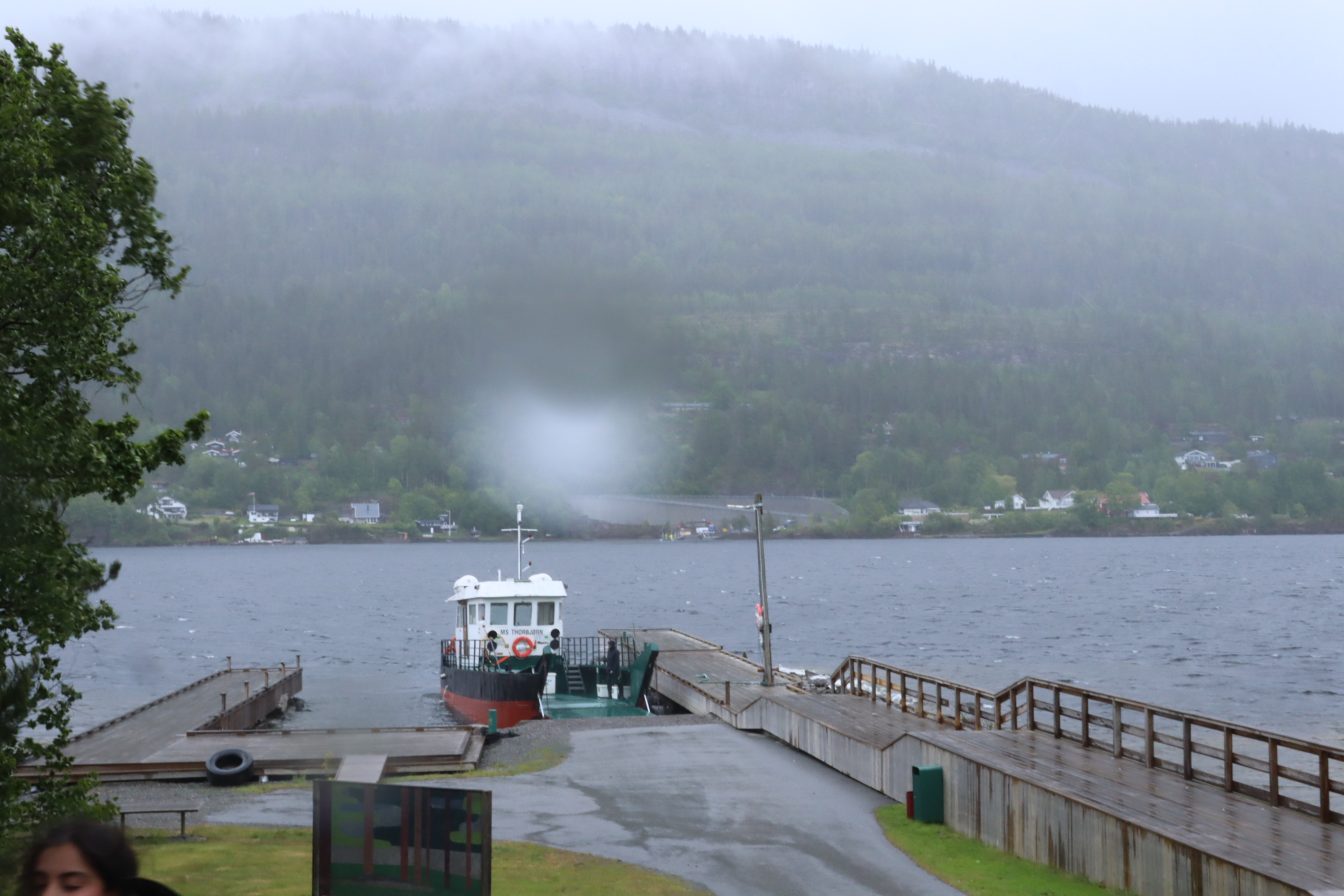 Vy över ett disigt Utoya. En båt har lagt till vid bryggan.