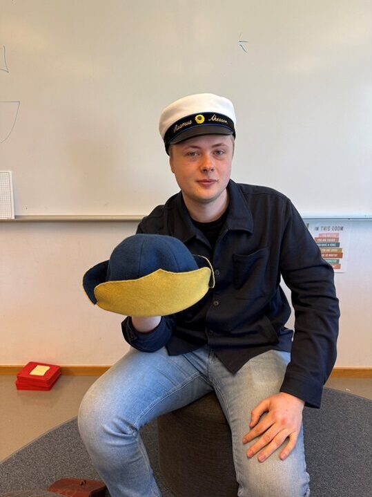 Rasmus med studentmössa på sig håller i en Karolinerhatt.