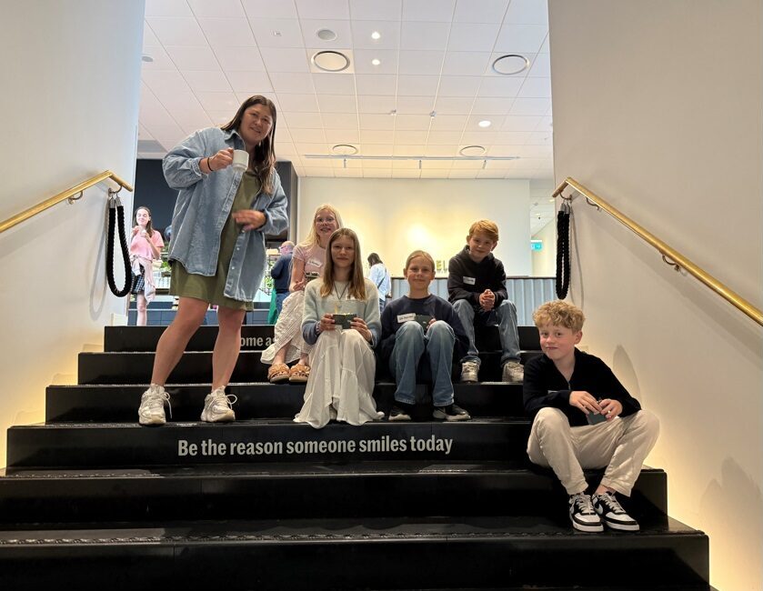 Lärare och elever i en trappa där det på ett steg står 'Be the reason someone smiles today'.