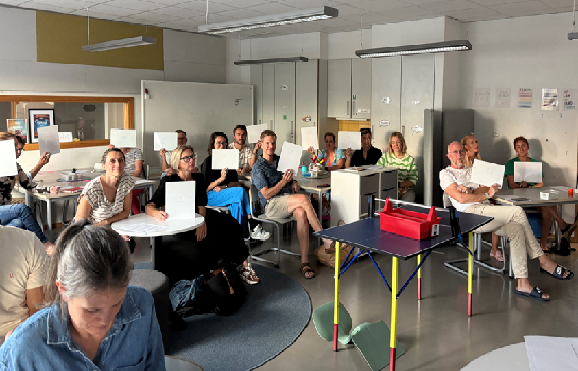 Vårdnadshavare sitter på elevernas platser i klassrummet under föräldramötet.