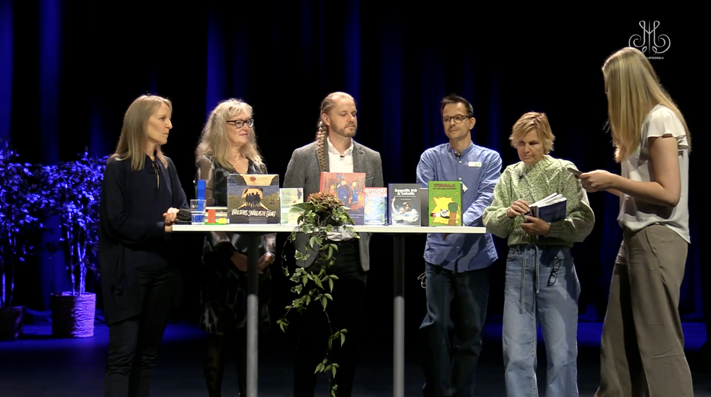 En grupp bestående av forskare, pedagoger och skolbibliotekarier intervjuas på en scen.