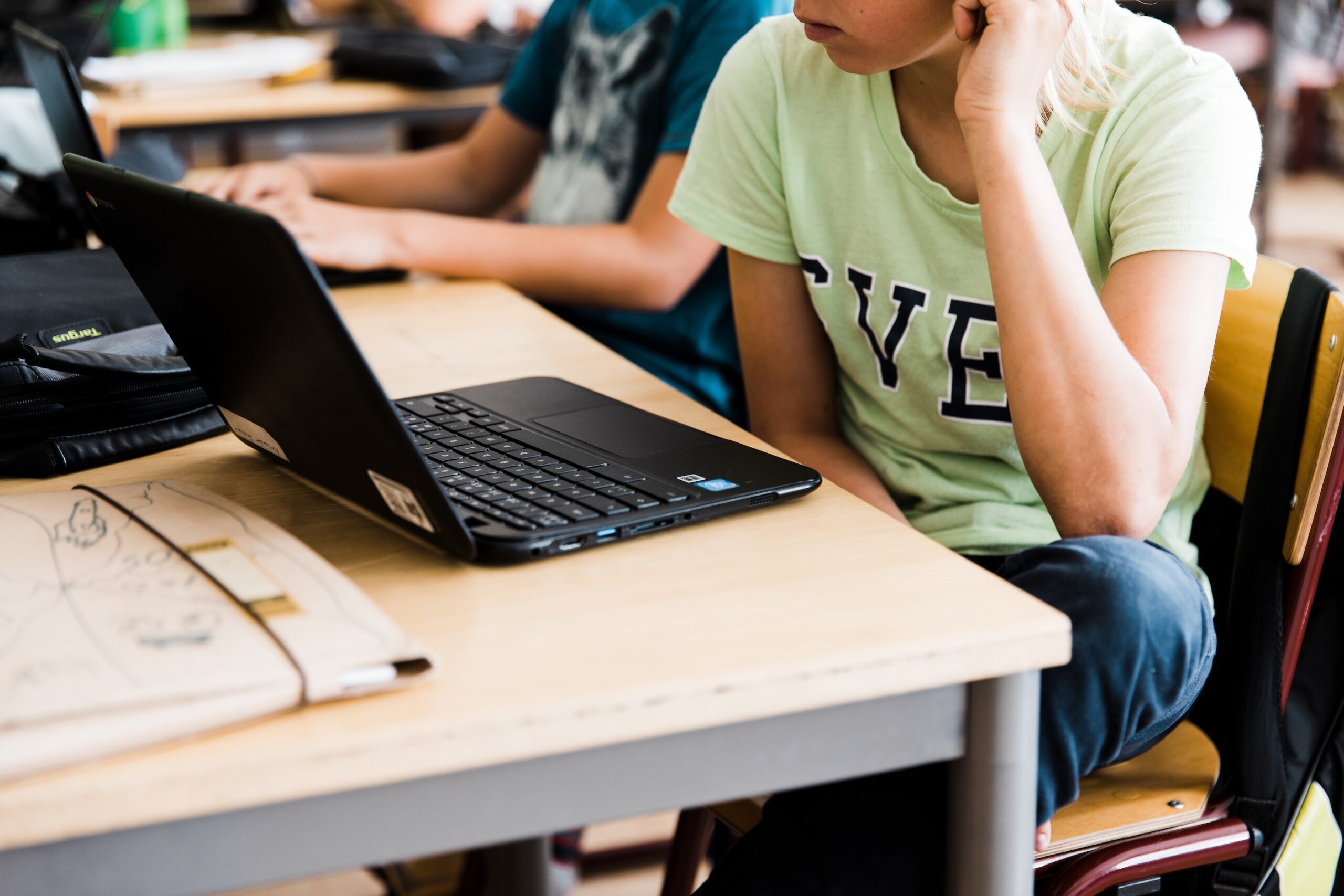 Elev arbetar vid skolbänk med bärbar dator under lektion, fokus på digitalt lärande och studieteknik.