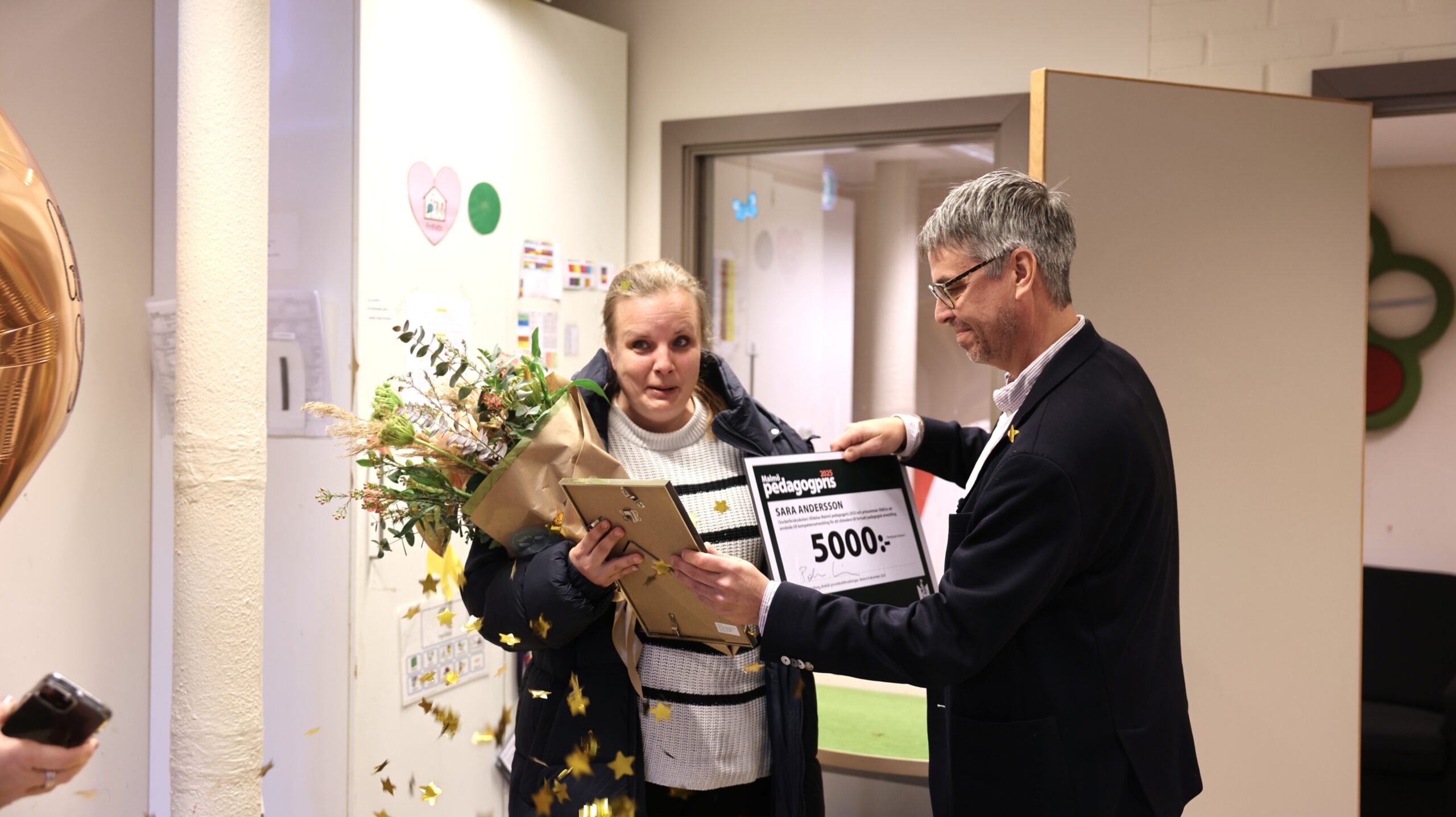 Pedagogprisvinnare står med blombukett.