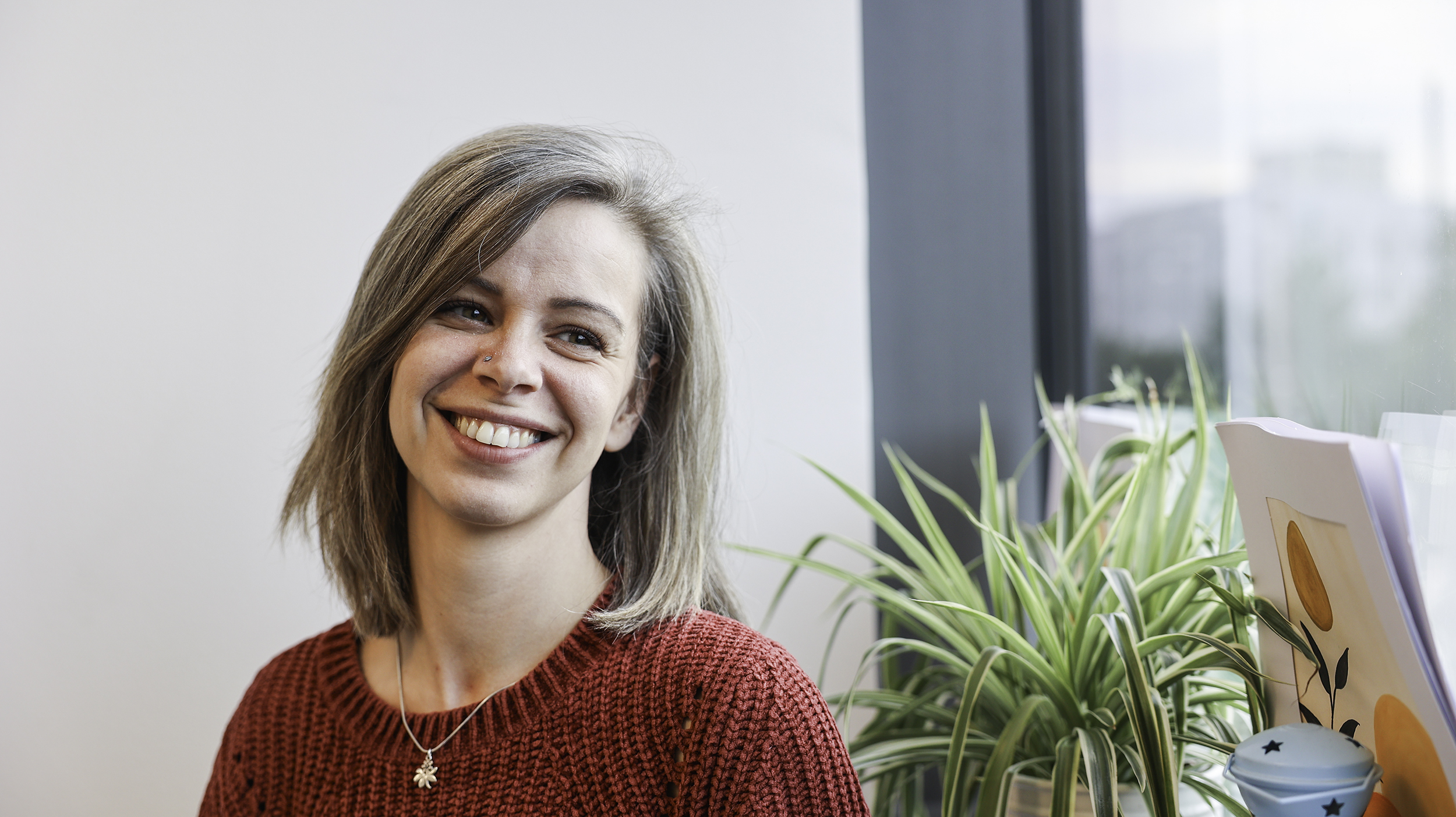 Kvinna står vid fönster och ler.