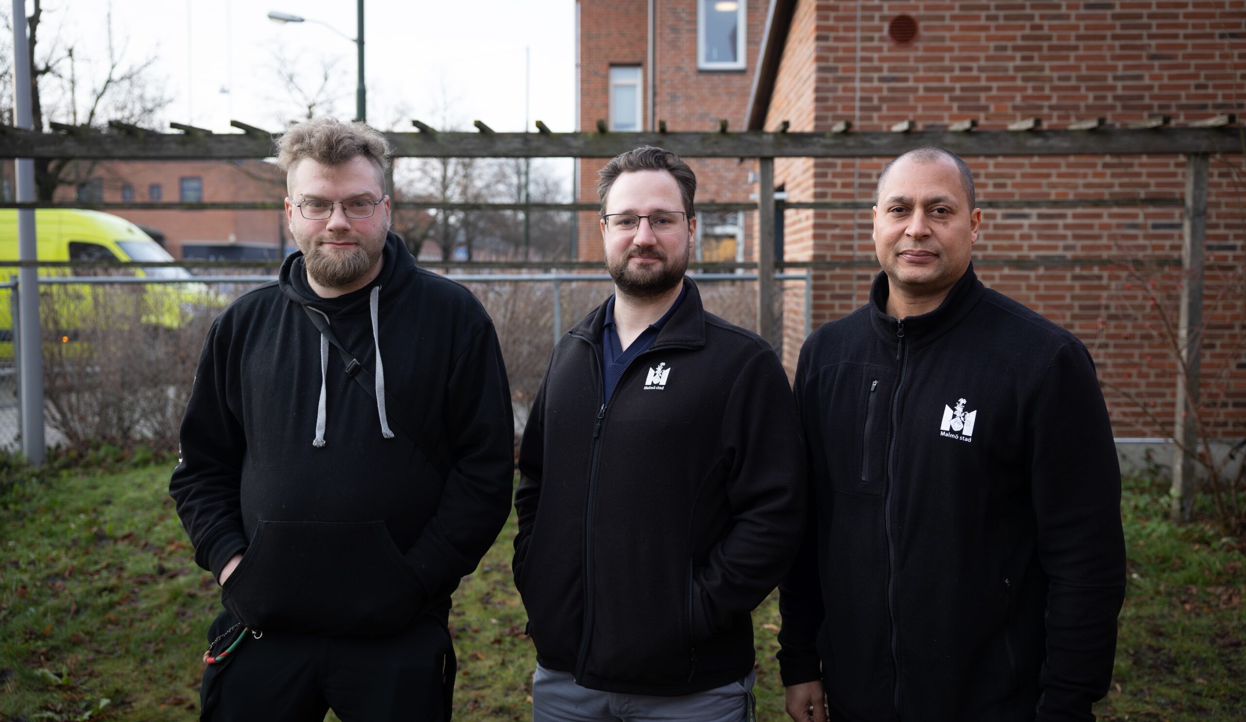Tre medarbetare står utomhus framför skolans tegelbyggnad i Malmö.