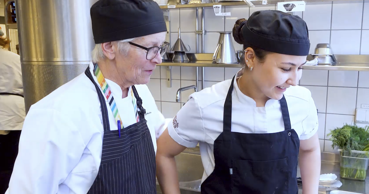 Lärare och elev arbetar tillsammans i kök under en praktisk lektion.