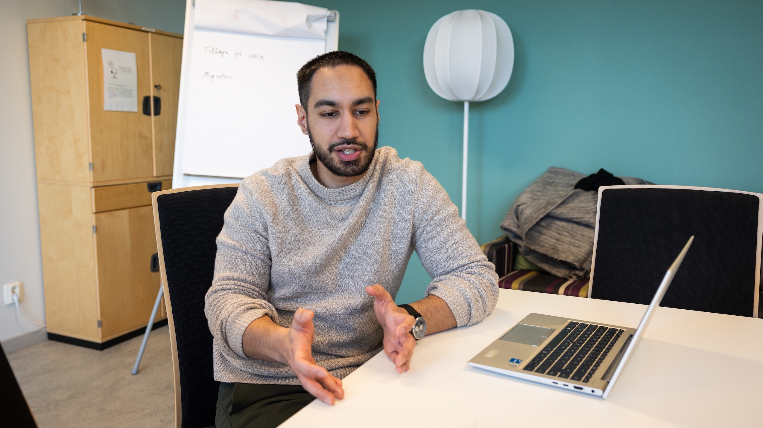 Person i samtal vid ett bord med laptop i ett mötesrum.