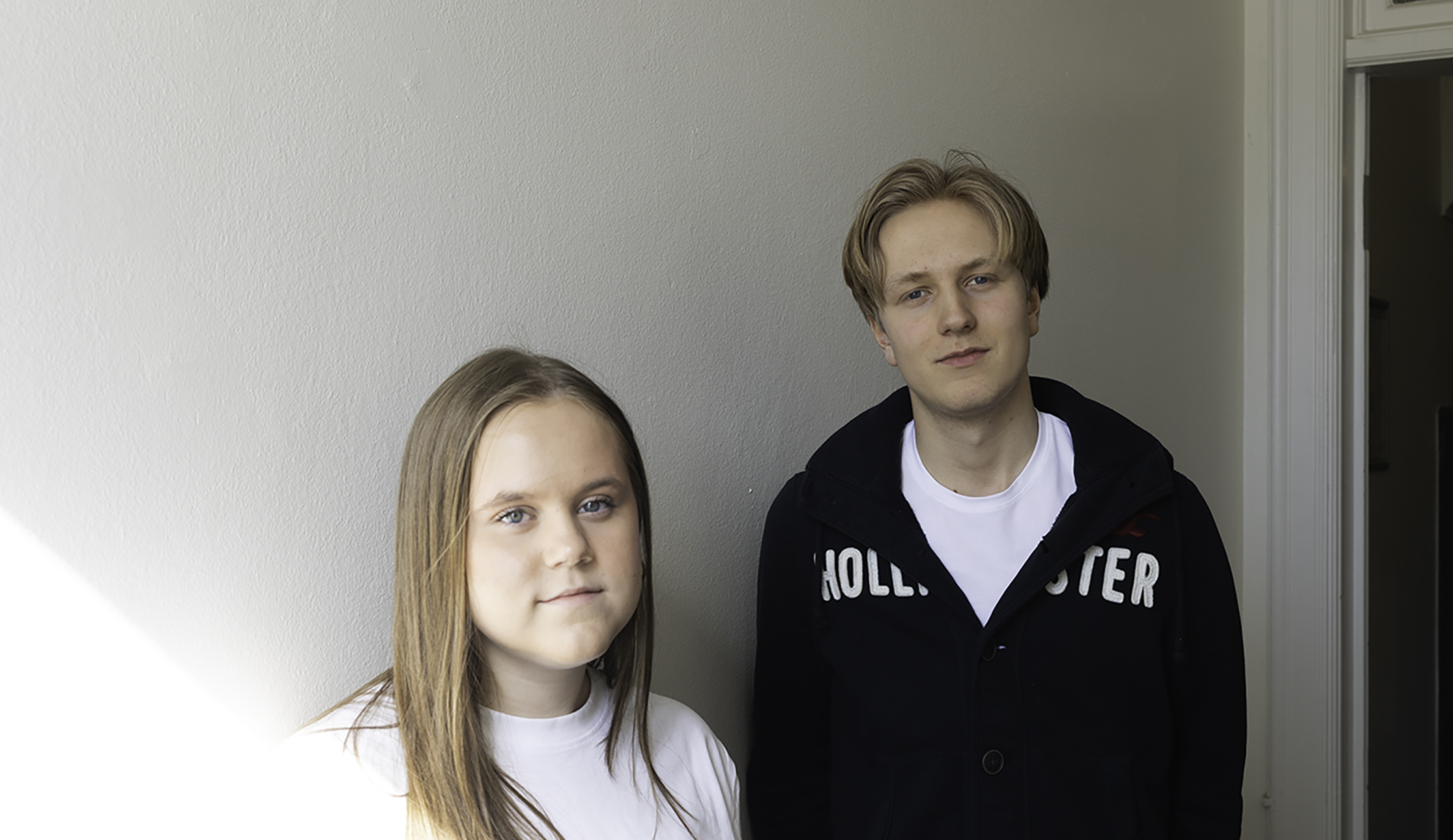 Två elever står framför vit vägg.