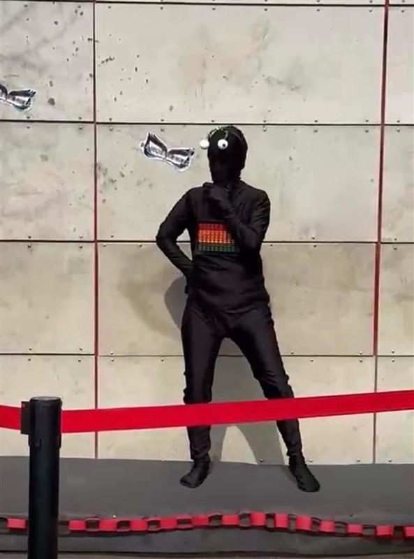 En svartklädd person med antenner uppträder på skolgården i masked singer.
