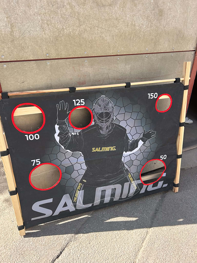 Skottramp för innebandy med en målvaktsbild och fem hål märkta med olika poäng: 50, 75, 100, 125 och 150.